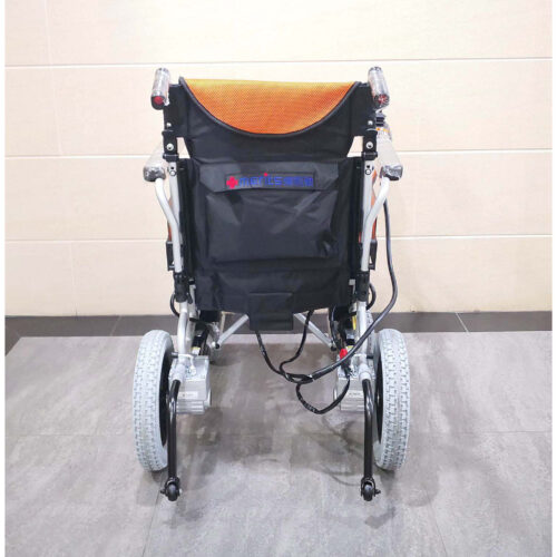 輪椅王 輕巧、可折疊的台灣品牌Merits WP902電動輪椅配有橙色座椅和靠背、黑色扶手、操縱桿控制器和腳踏板，靠在瓷磚牆上。