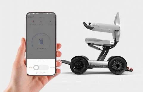 輪椅王 一隻手拿著智慧型手機，螢幕上顯示應用程式介面，旁邊是一個緊湊、具有未來感的 Robooter X40 折疊電動輪椅。