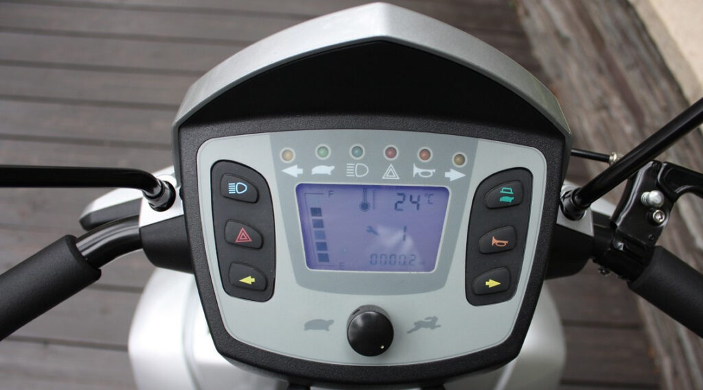 輪椅王 Merits S940大型四輪代步車/輪椅的儀表板顯示器配有各種控制按鈕、數位車速表以及電池電量、溫度和里程表讀數指示器。