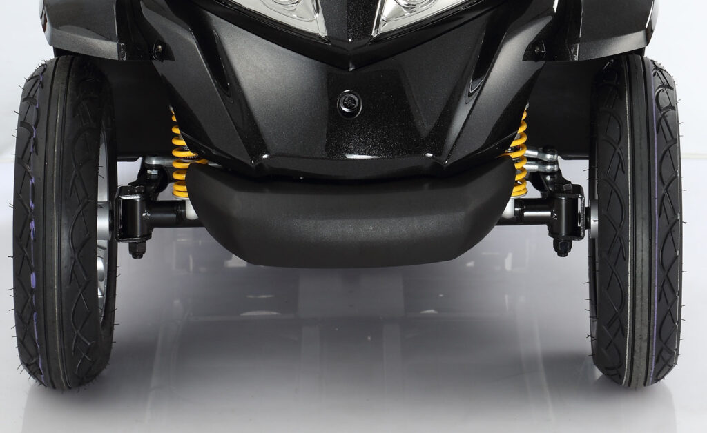 輪椅王 黑色 Merits S940 大型四輪代步車的前懸吊和車輪的特寫視圖，明顯強調黃色減震器和光滑的黑色輪胎。