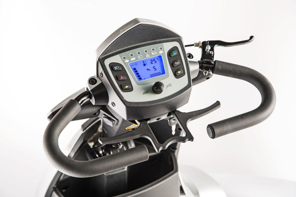輪椅王 Merits S940 大型四輪代步車電動滑板車控制面板的特寫視圖，配有數位顯示屏，顯示速度、電池電量和溫度，車把和煞車桿可見。