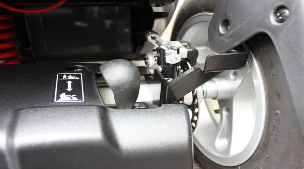 輪椅王 帶有鏈條和輪子的機械部件的特寫視圖，帶有 Merits S940 大型四輪代步車的安全說明標籤。