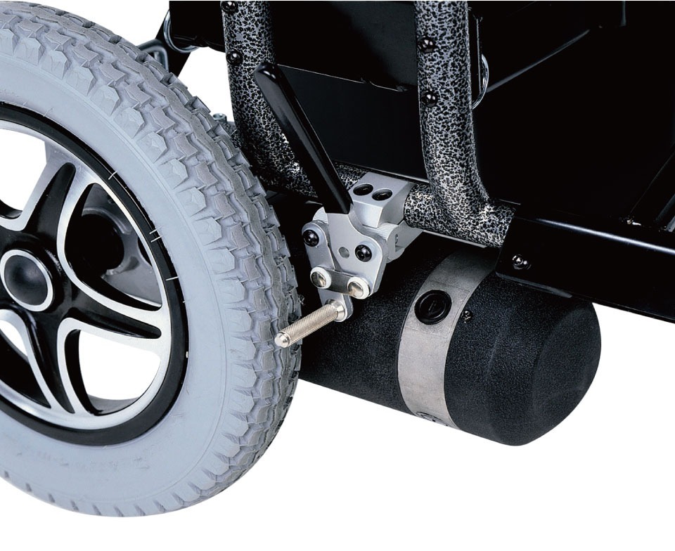 輪椅王 Merits WCP183 超重人員電動輪椅（700 磅承重）車輪及其懸吊系統的特寫，顯示充氣輪胎和連接到框架的黑色氣缸。