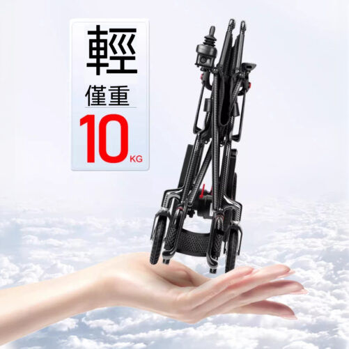 輪椅王 折疊的黑色碳纖電動輪椅carbon Plus 握在手上方，上面有文字表明在多雲的天空背景下重量僅為 10 公斤。
